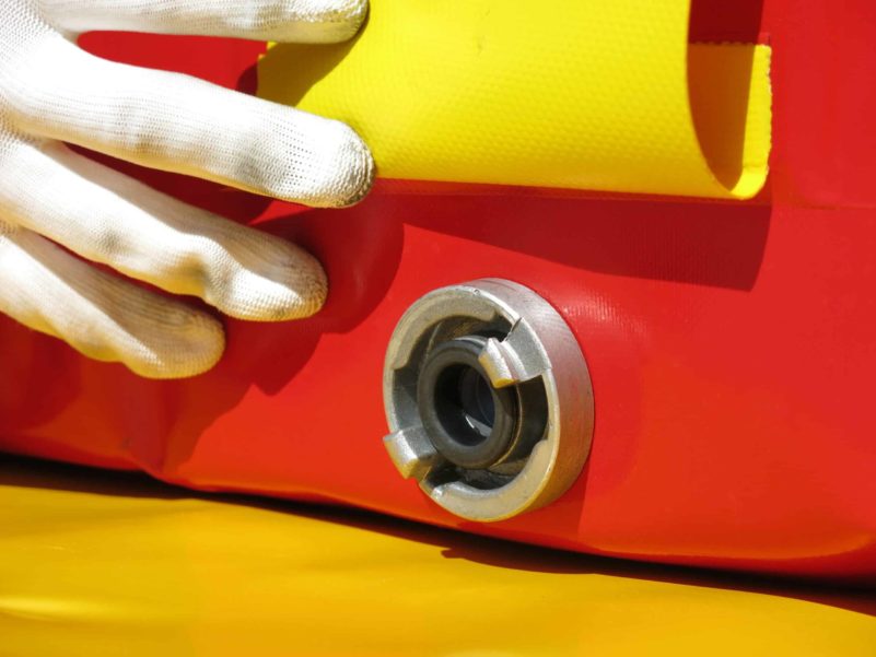 Close-up of inflatable boat valve with hand in gloves.