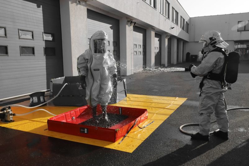 Firefighters in hazmat suits conducting decontamination exercise.