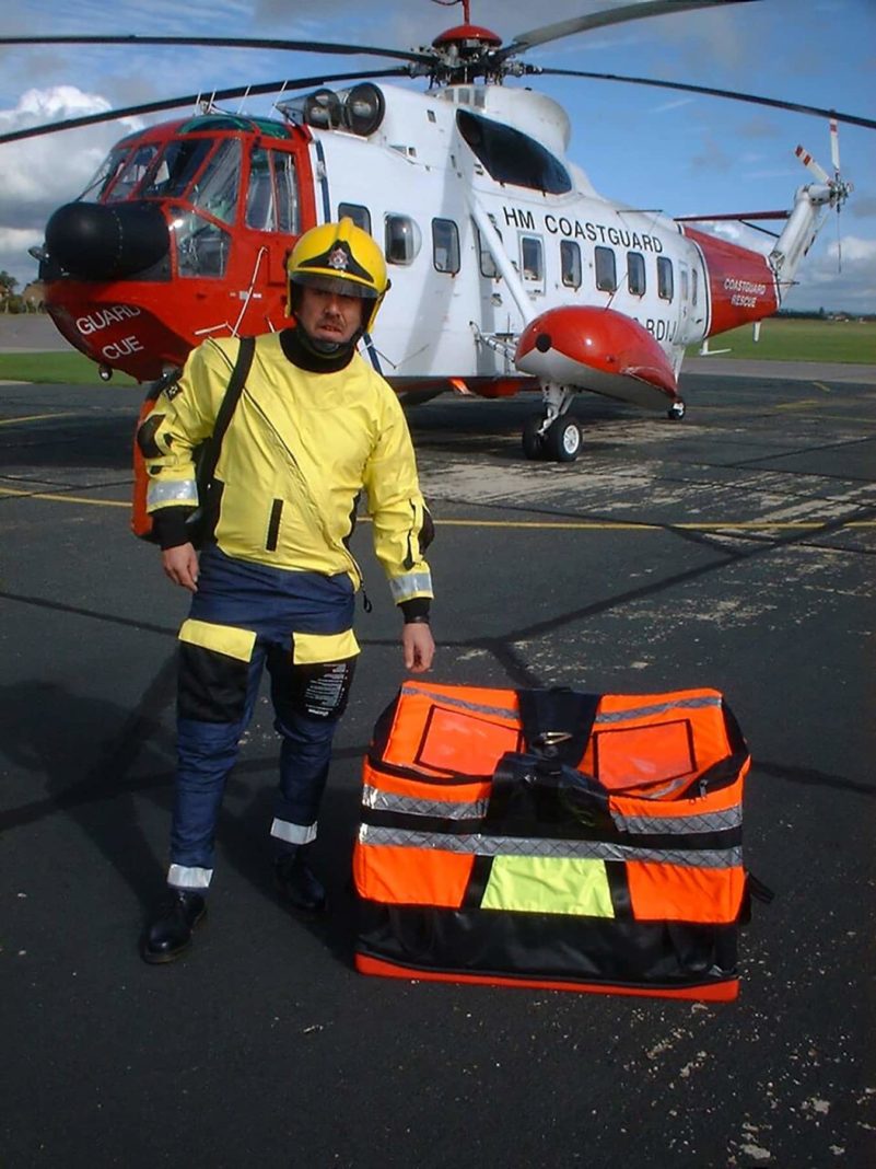 Coastguard rescuer with helicopter and emergency equipment.