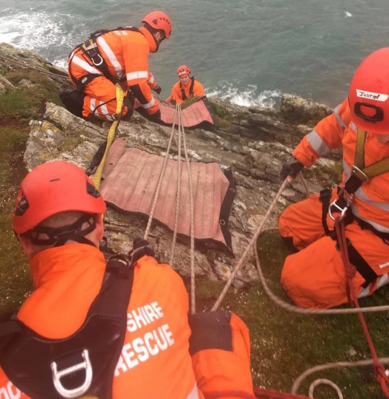 Rescue team training on rocky cliff near the sea.