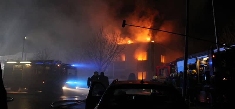 Firefighters battling a large building fire at night.