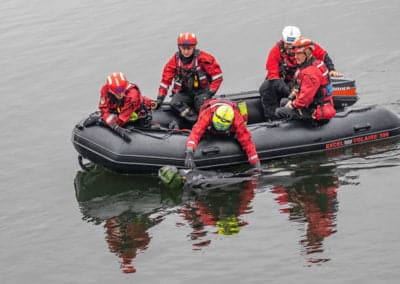 Rescue team retrieving object from water in a boat.