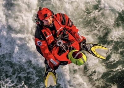 Rescue diver in action above turbulent waters.