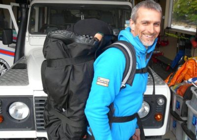 Man with backpack standing in front of mountain rescue vehicle.