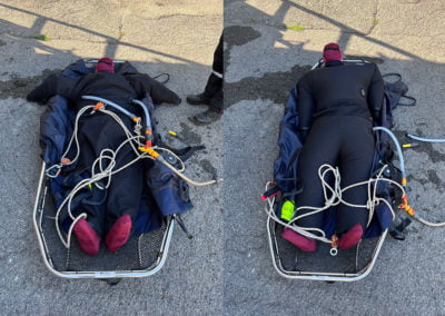 Dummy in diving gear secured on stretcher during training exercise.