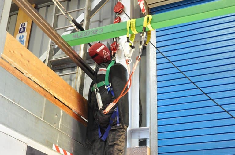 Construction worker using fall protection safety harness.