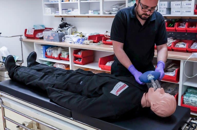 Instructor demonstrating CPR on a medical mannequin.