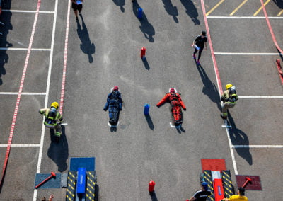 Firefighters in a training exercise, dragging dummies on ground.