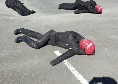 Motorcyclists practising emergency slide technique on tarmac.