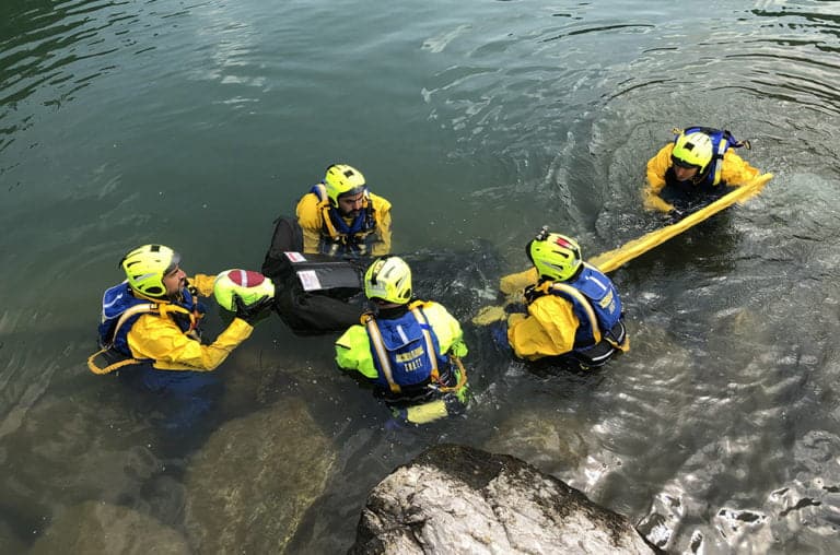 Rescue team training in water with safety equipment.
