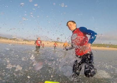 People running in wetsuits during surf lifesaving competition.