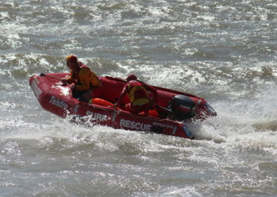 Rescue team on motorboat navigating rough water.