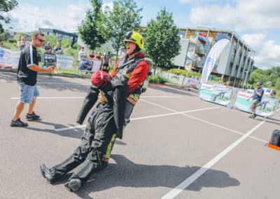 Firefighter in gear carrying dummy during rescue drill.