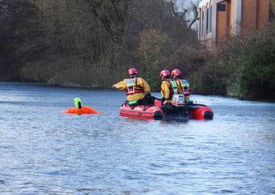 Rescue team aiding person in river.