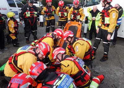 Rescue team in yellow working on injured individual.