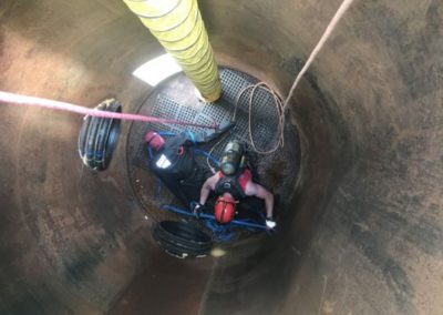 Worker performing confined space entry in an industrial tank.