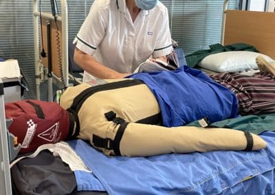 Nurse practising patient care on a medical training mannequin.