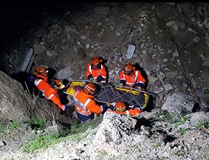 Rescue team assists person in rocky terrain at night.