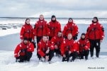 Group in red jackets standing on snowy landscape.