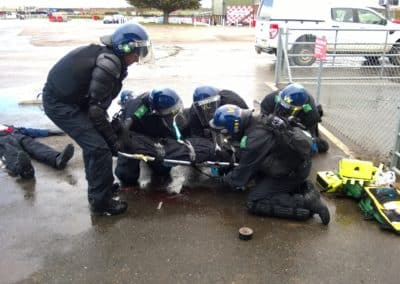 Police in riot gear attending to injured individuals.