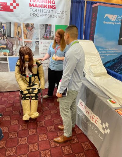 Healthcare professionals discussing training manikins at Ruth Lee stand.