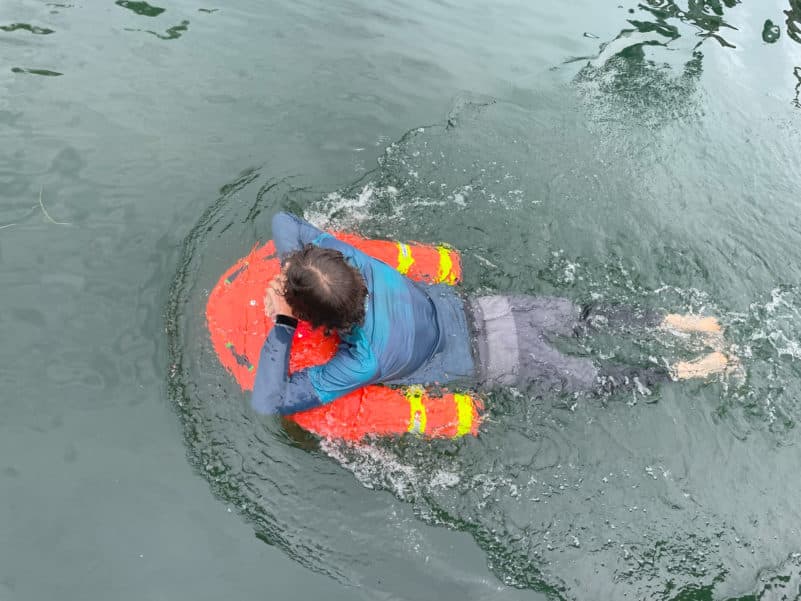 Person swimming with orange buoy fast rescue devic ein water