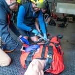 Rescue team training with mannequin in safety gear.