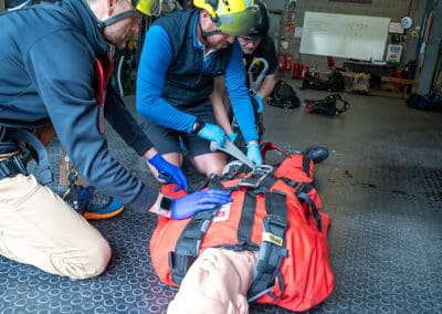 Rescue team training with mannequin in safety gear.